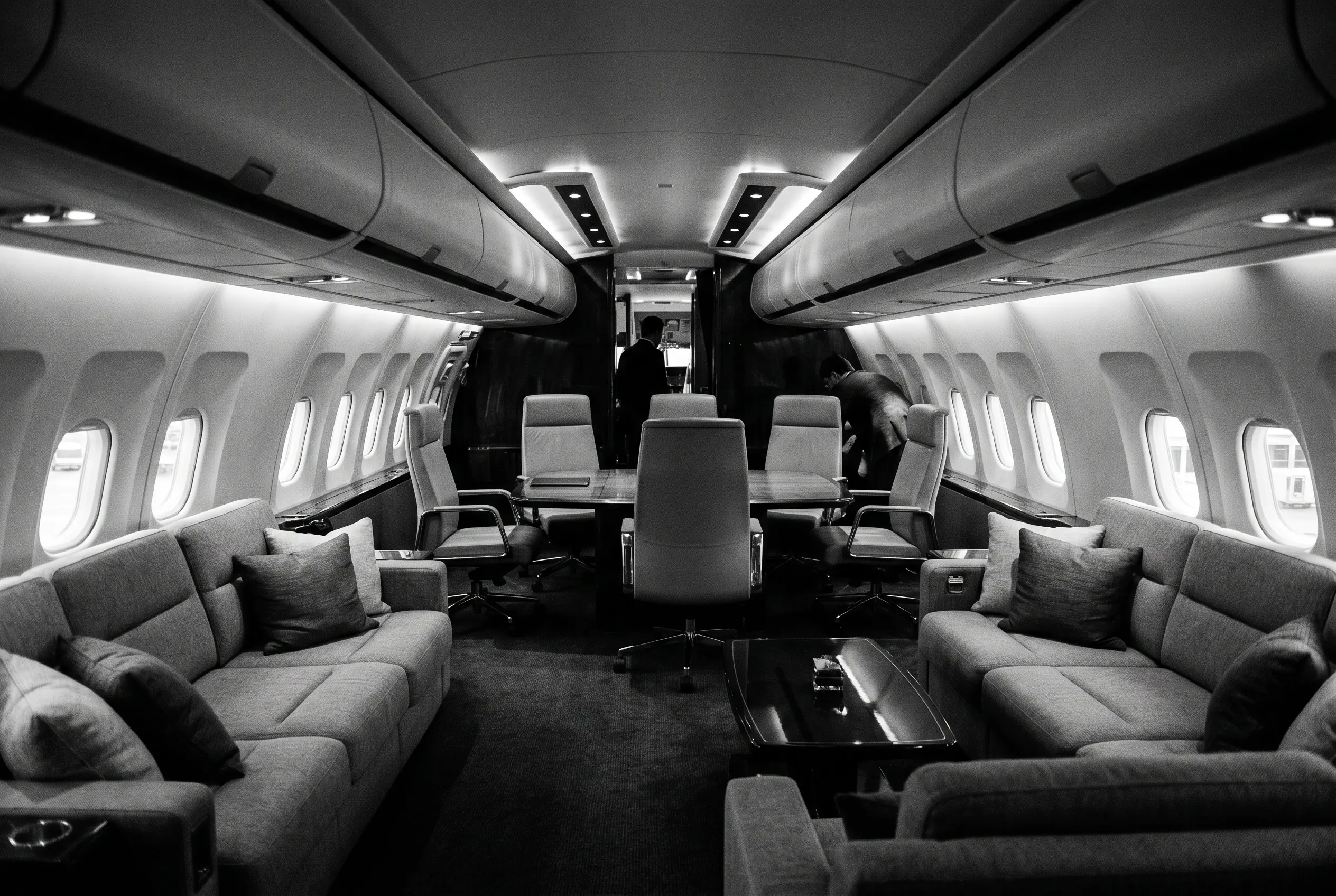 Airbus ACJ319 VIP lounge with sofas and a conference area for a New York to Miami charter, in monochrome