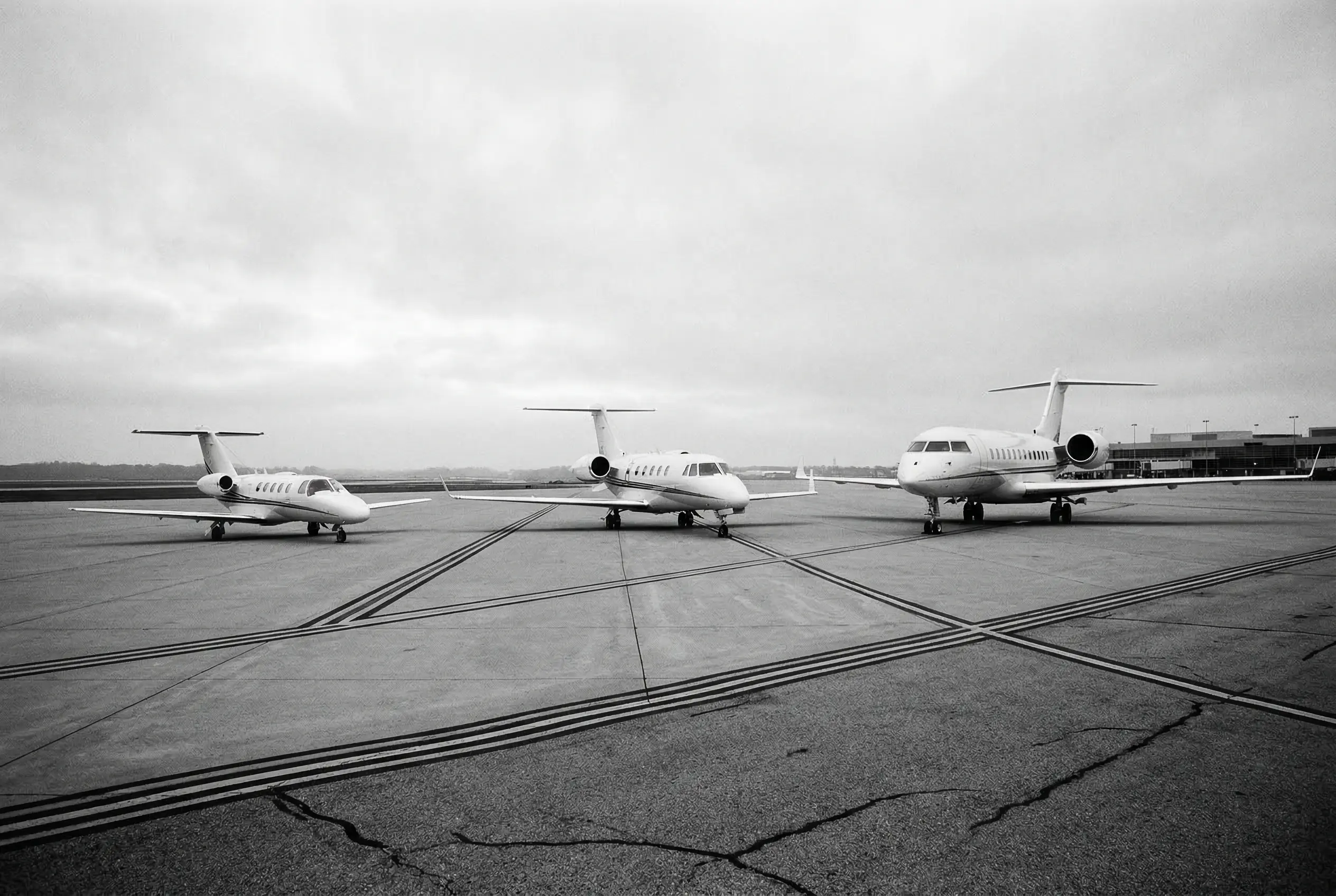 Three private jets of different sizes lined up on the tarmac