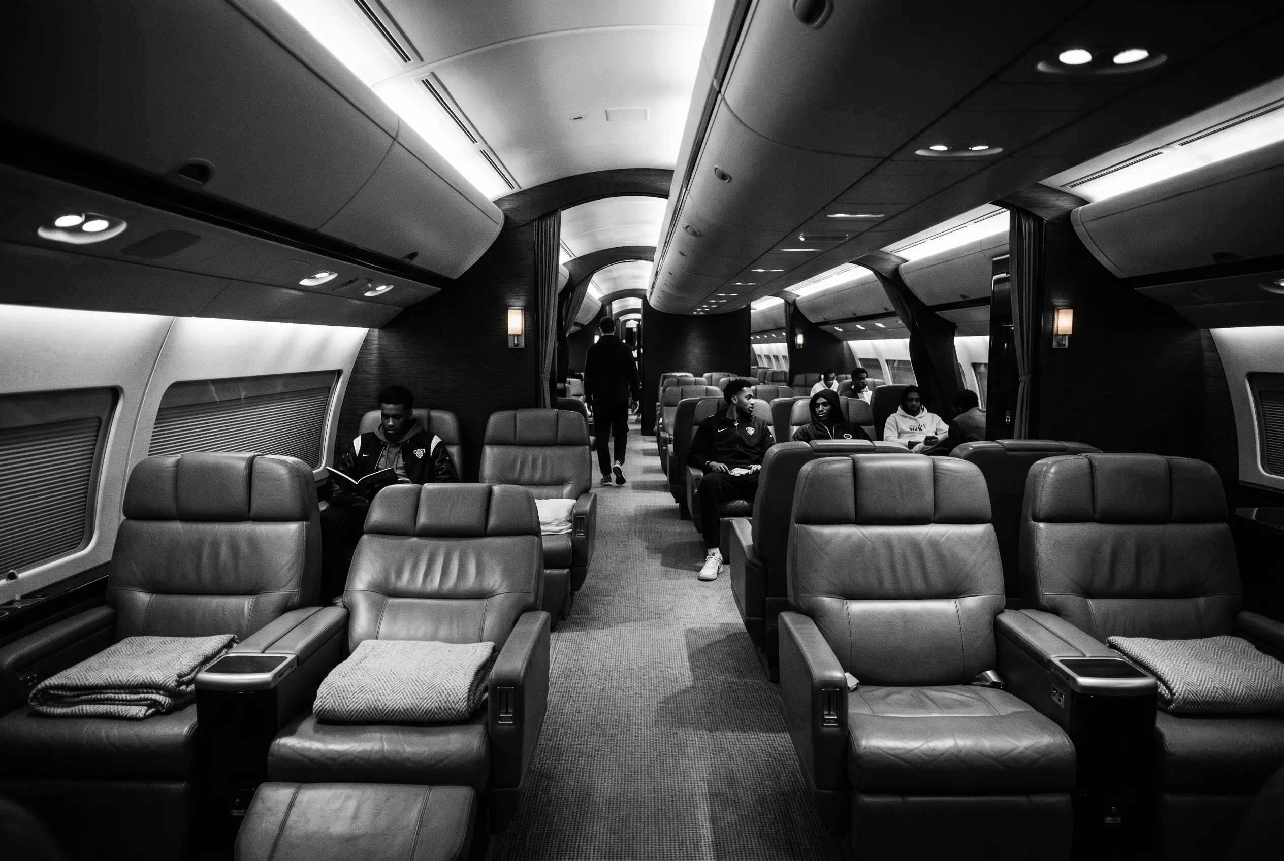 Wide jet cabin configured for a sports team travelling from New York to Miami, in black and white