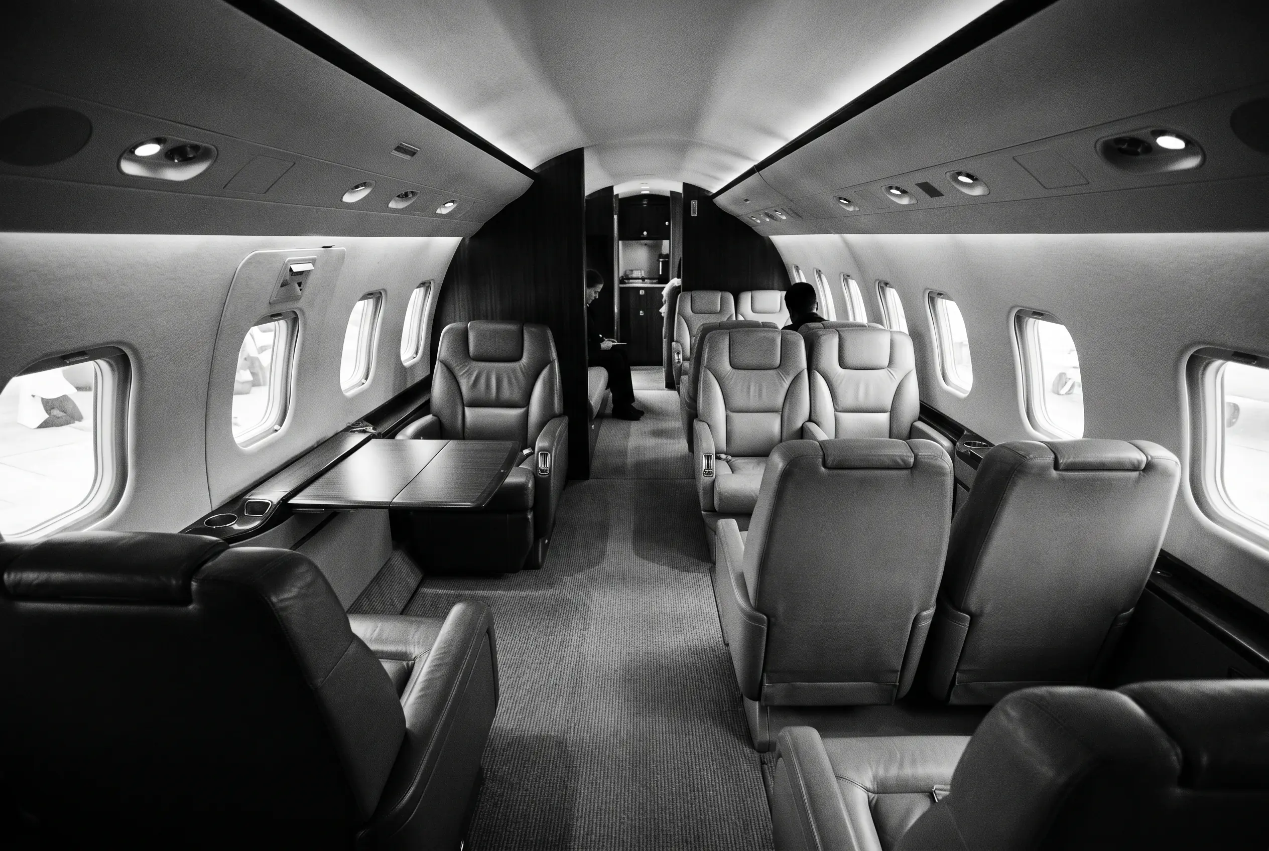 Wide flat-floor super-midsize jet cabin for a New York to Miami charter, in monochrome
